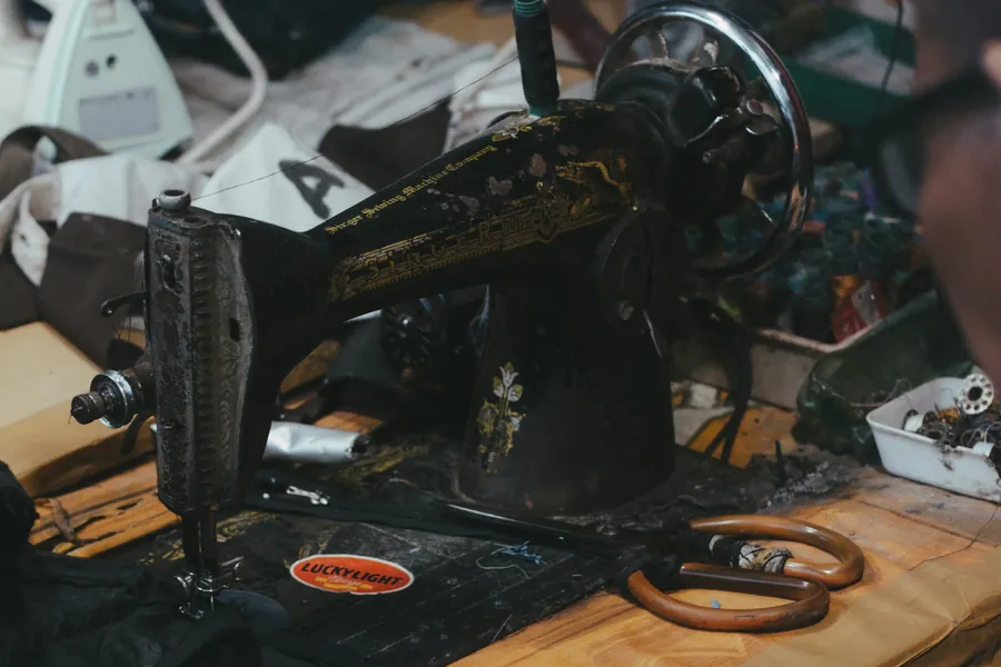 A sewing machine lit from the side in a dim garment workshop.