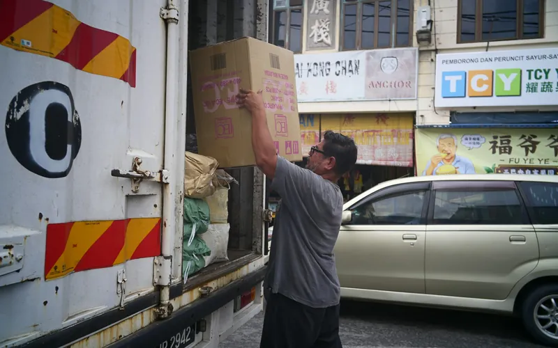 A delivery being loaded outside a row of shops.