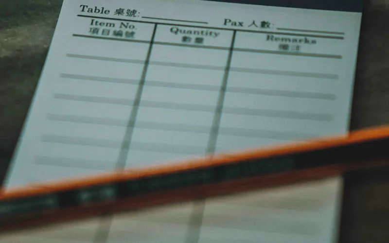 A paper order pad and pencil on a counter.