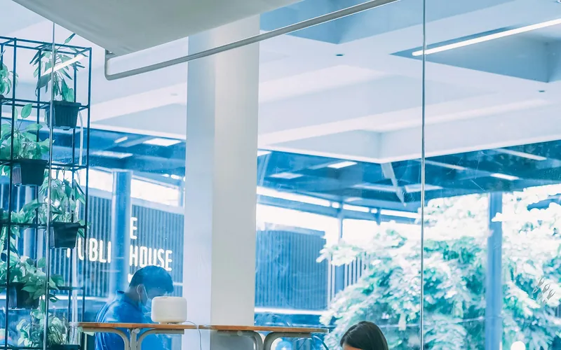 A person working at a desk in a bright, plant-filled workspace.