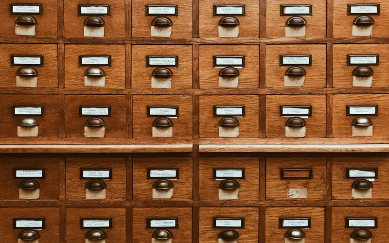 A wall of wooden card-index drawers with brass label holders.